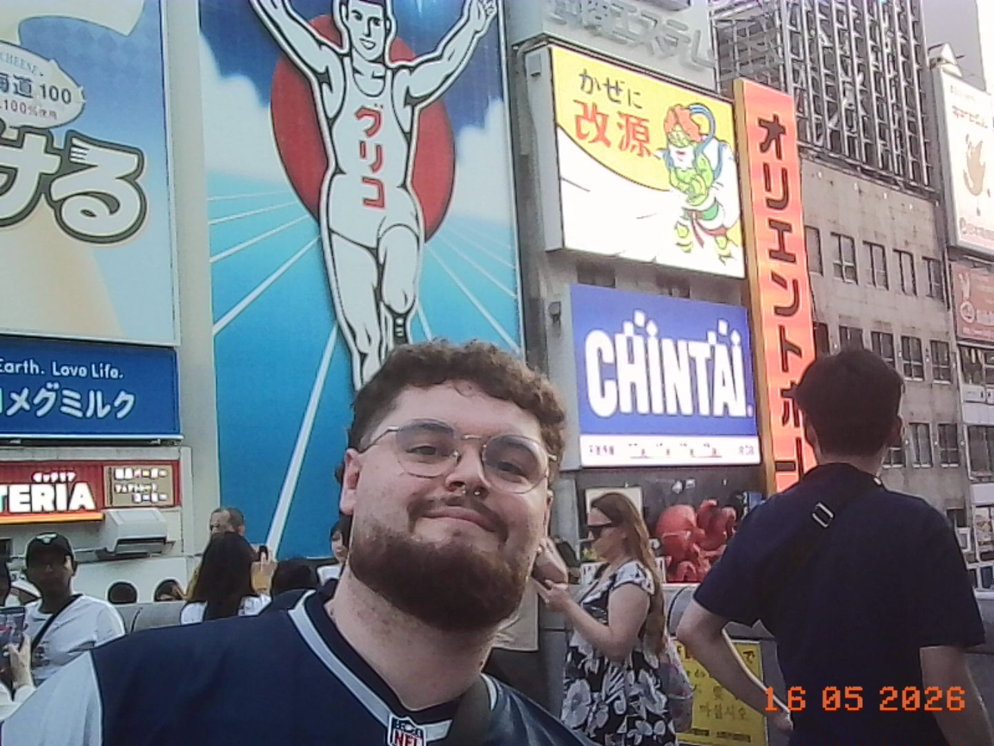 Juanma, desarrollador detrás de Omen Monkey, en Osaka con carteles luminosos de fondo.